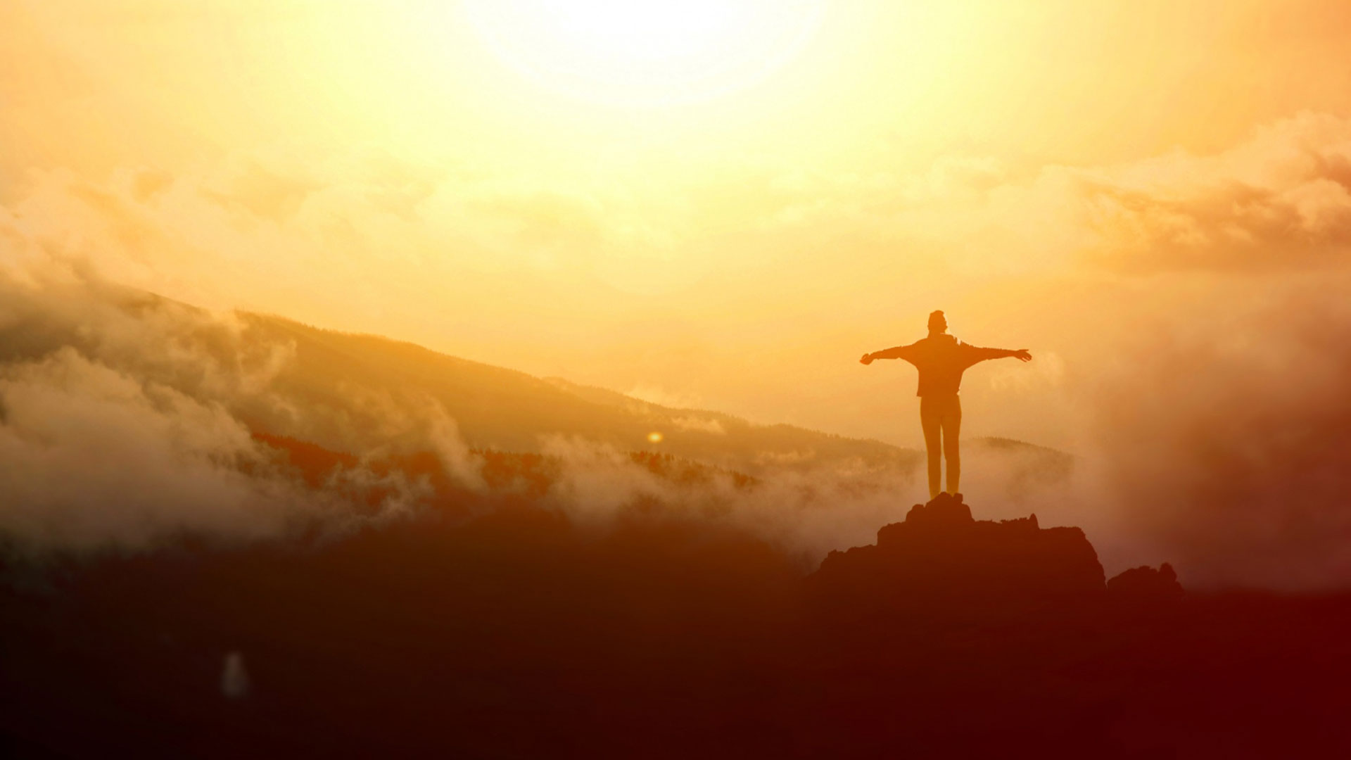 Picture of a person with open arms standing on a high area overlooking an expansive, sunlit view. | Image: Freepik