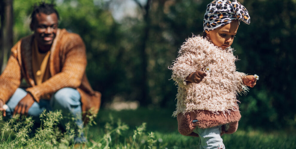 A parent looks at his daughter from a slight distance as they explore the outdoors. | Image: Imani Montessori School